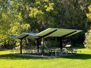 covered picnic shelter with picnic tables surrounded by trees