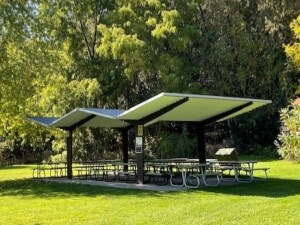 covered picnic shelter with picnic tables beneath surrounded by trees