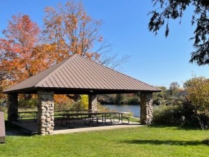 covered picnic shelter with picnic tables beneath and beside the river
