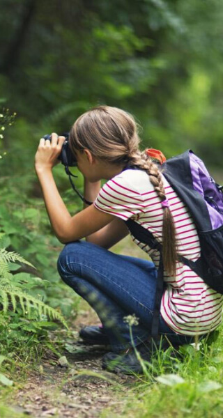 girl taking a picture in the woods