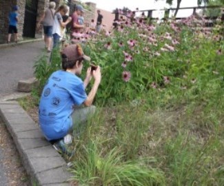 Boy near garden taking photo of flowers