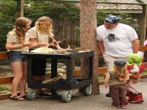 volunteer with mobile cart holding antlers for young visitors to touch