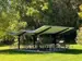 covered picnic shelter with picnic tables beneath surrounded by trees
