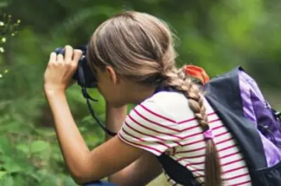 girl taking a picture in the woods